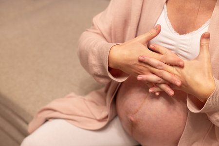 Pregnant woman massaging swollen fingers. Swollenness and wrist ache during pregnancy.の写真素材