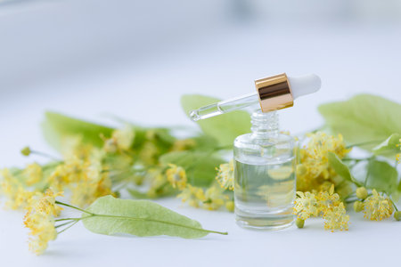 linden extract in a small glass bottle with linden flowers around. Selective focus.の写真素材