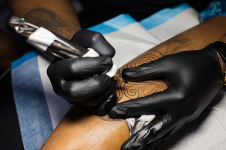 Hands of tattoo artist in black gloves busy with work.の写真素材