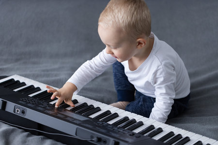 Smiling little child pushes buttons on electric piano.の写真素材