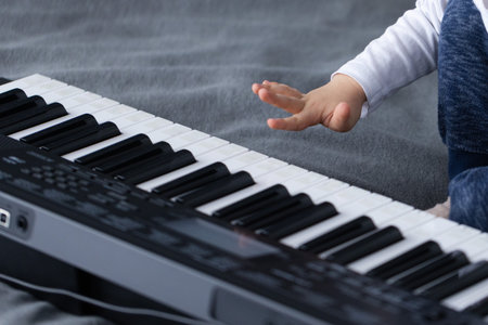 Kid wants to touch keys of piano with his finger. Closeup.の写真素材