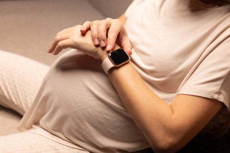 Pregnant woman with watches. Pregnant woman looking at her watches.