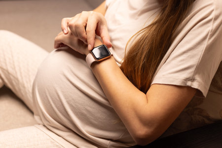 Pregnant woman looking at her watch.