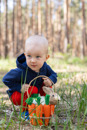 Portrait of little child sitting in the park with Easter basket.