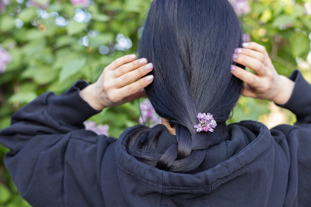 Dark haired girl with flowers in the hair. Sprig lilac flowers.