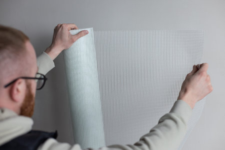 Man holding a roll of white plaster mesh for preparatory and painting works.