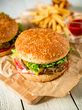 Tasty hamburger with beef, sauce and french fries on wood background. Flat lay. Top view.の写真素材
