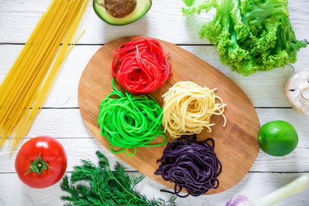 Multicolored pasta on a plate and vegetables isolated on white wood background. Flat lay. Top view. Asian foodの写真素材
