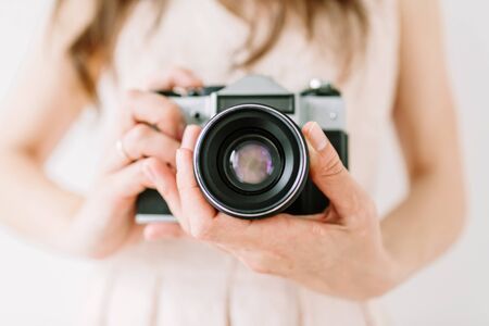 Young woman holding in hands of old vintage camera. Girl photographer and film cameraの写真素材