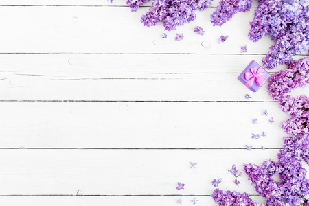 Floral pattern of lilac branches, petal and pink box for rungs on a wooden background. Flat lay, top view.の写真素材