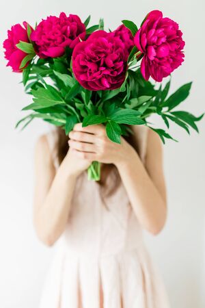 Happy young woman holding in hands peony bouquet. Woman in pink dress. Sweet traditional momentの写真素材