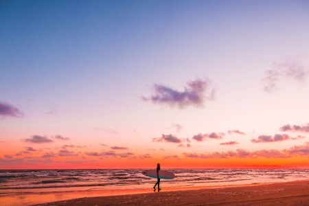 Sporty girl go to surfing. Woman in wetsuit and sunset or sunrise on ocean