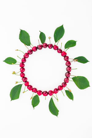 Cherries and leaves on white background. Flat lay. Top view. Round frameの写真素材