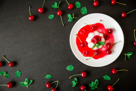 Panna cotta with cherry syrup and berries in a plate on a dark background, traditional italian dessert. Flat lay. Top viewの写真素材