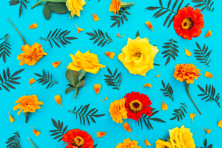 Floral pattern made of yellow and red flowers with petals on blue background. Flat lay, top view. Floral background.の写真素材