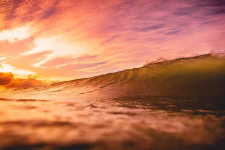 Wave in the ocean at sunset or sunrise. Wave and sun light with cloudy sky