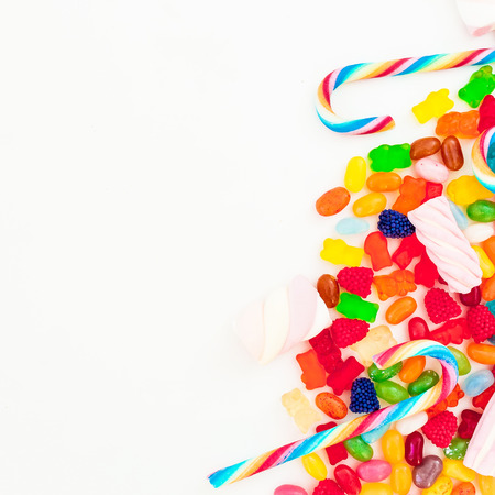 Assorted colorful bright candies and sugar cane on white background. Flat lay, top viewの写真素材