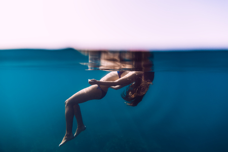 Woman floating in the ocean, girl is relaxing. Underwater photoの写真素材