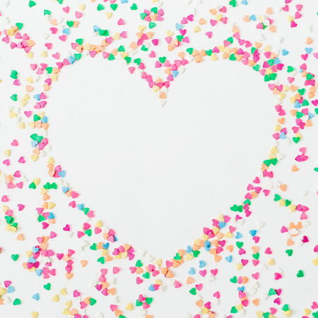 Heart symbol made of colorful bright confetti on white background. Flat lay, top view copy space. Love conceptの写真素材