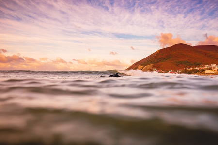 Wave in the ocean at bright sunset or sunrise with surfer.の写真素材