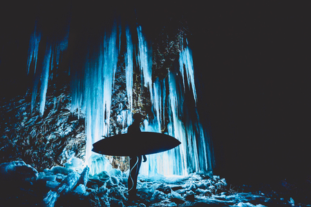 Surfer in night and big icicles with illumination. Cold weather. Winter surfingの写真素材