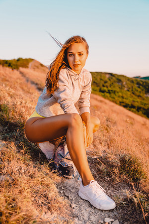 Smiling attractive woman in nature at sunset. Happy girl traveler on a walk in the mountainsの写真素材