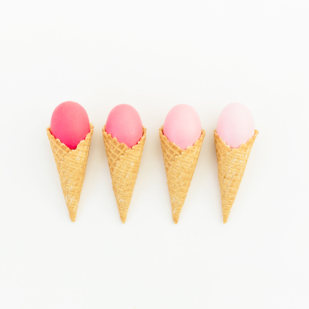 Pink Easter eggs in waffle cone on white background. Flat lay. Top view. Creative holiday concept.の写真素材