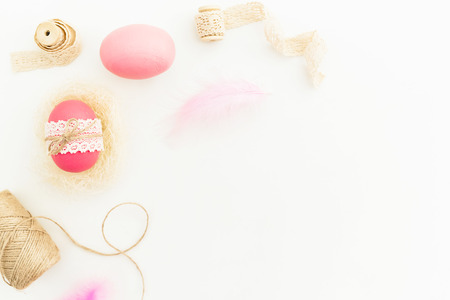 Frame of Easter pink eggs with twine, feathers and tapes on white background, Top view, Fat lay. Easter holidayの写真素材