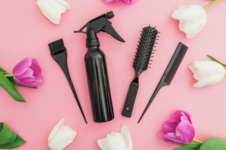 Hairdresser tools - spray, combs and tulips flowers on pink background. Beauty concept. Flat lay, top viewの写真素材