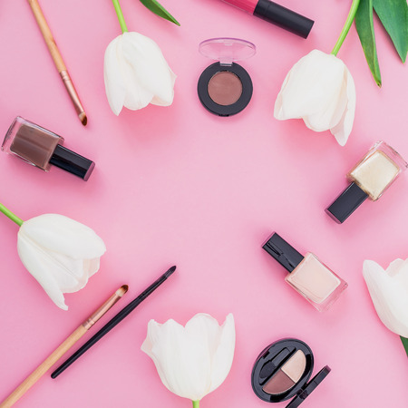 Beauty composition with white tulips and cosmetics on pink background. Top view. Flat lay home feminine desk.の写真素材