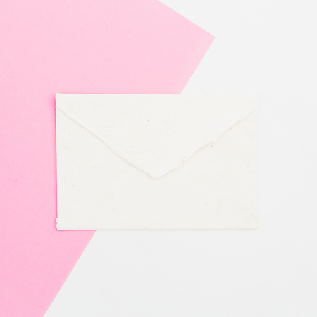 Paper envelope on white and pink background. Flat lay. Top view