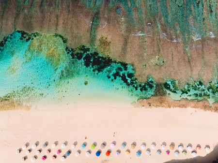 Top view of beautiful sand beach with turquoise sea water and colorful umbrellas, aerial drone shotの写真素材