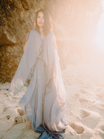 Bride posing in blue wedding dress in a beach at sunset or sunrise colors. Wedding style.の写真素材