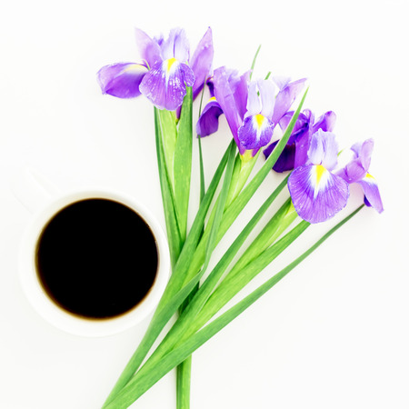Bouquet of Iris flowers with mug of black coffee on white background. Flat lay, Top view.の写真素材