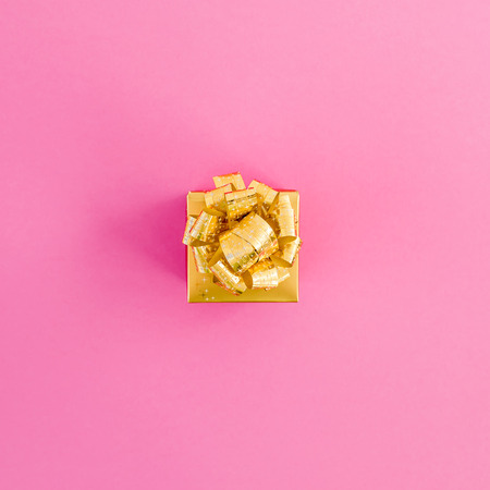 Golden gift box on pink background. New year holidays. Flat lay. Top viewの写真素材