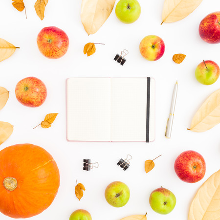 Autumn composition of fall leaves, apples and pumpkin with notebook, pen and clips on white background. Thanksgiving day. Flat lay, top viewの写真素材