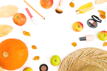Thanksgiving dinner frame made of fall leaves, feminine cosmetics and apples and pumpkin on white background. Flat lay, top viewの写真素材