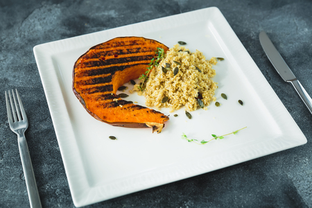 Fried pumpkin with sprouted millet and pumpkin grains on the dark table. Thanksgiving day foodの写真素材