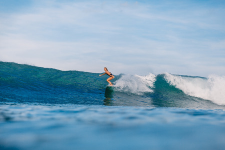 Professional surf girl at surfboard ride on wave wave. Woman at waveの写真素材
