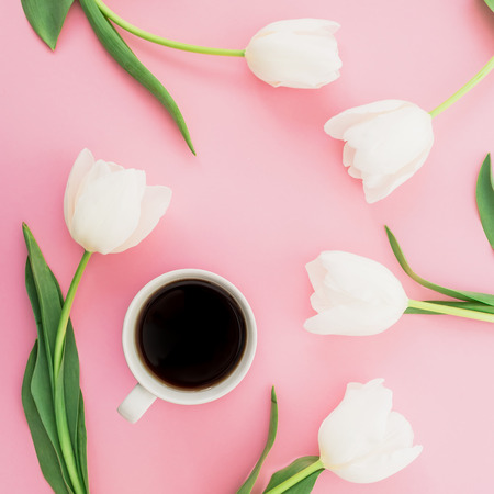 Spring composition with tulip flowers and mug of coffee on pink background. Flat lay, top view.の写真素材