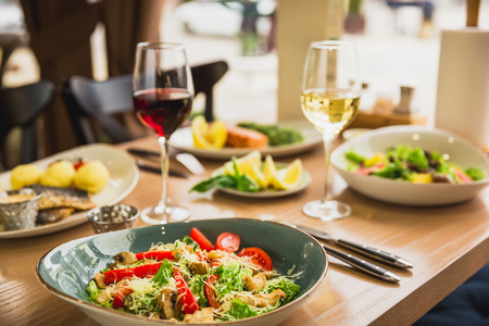 Festive dinner with tasty salads, fish dishes and glass of wine. Healthy food in cafeの写真素材