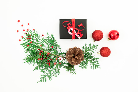 Merry Christmas composition with fir branches, black gift box and red balls with confetti on white background. Festive background. Flat lay, top viewの写真素材