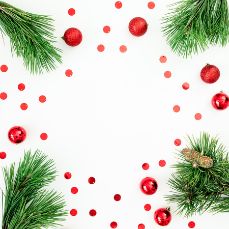 Christmas frame made of pine branches and red balls decoration with confetti on white background. Festive background. Flat lay, top viewの写真素材
