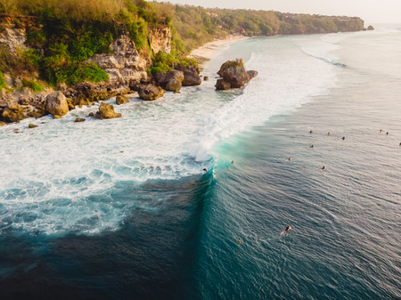 Aerial view with surfers and barrel wave in ocean