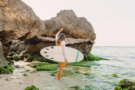 Attractive surf woman with surfboard going to ocean for surfing. Beautiful sporty woman.の写真素材