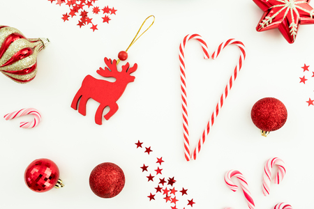 Christmas composition. Red toys, candy canes and confetti on white background. Flat lay, top view.の写真素材