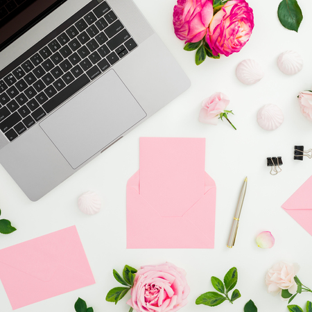 Laptop, roses flowers, diary, pen, envelope and marshmallow on white background. Flat lay. Top view. Feminine compositionの写真素材
