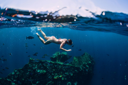Woman free diver dive in the tropical ocean at shipwreckの写真素材