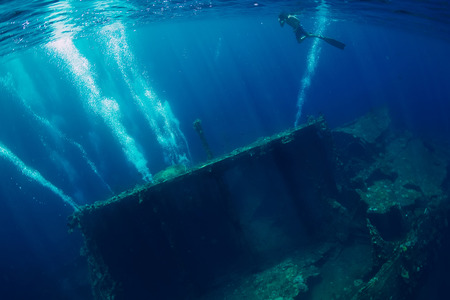 Freediver man swim in sea near shipwreck in Baliの写真素材