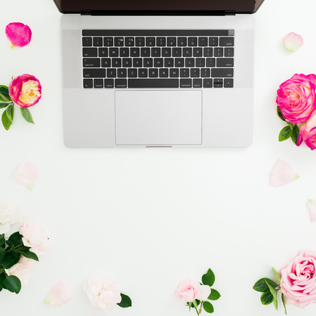 Laptop, roses flowers and petals on white background. Flat lay. Top view. Feminine compositionの写真素材